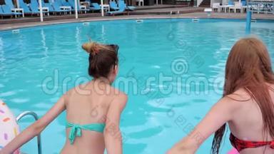 后景朋友们牵着手跳进蓝色的游泳池，快乐的女孩带着粉红色的充气戒指